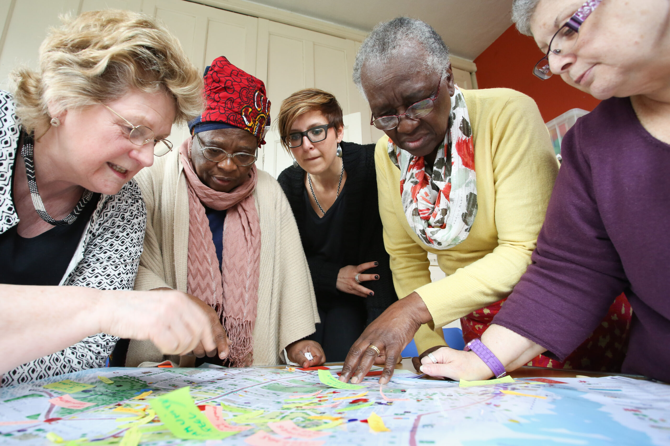 Four people doing an activity on a table with a large world map.