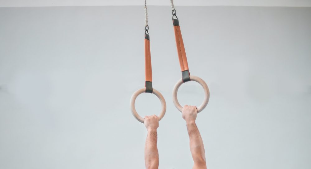 Closeup of a person's arms holding onto sports rings