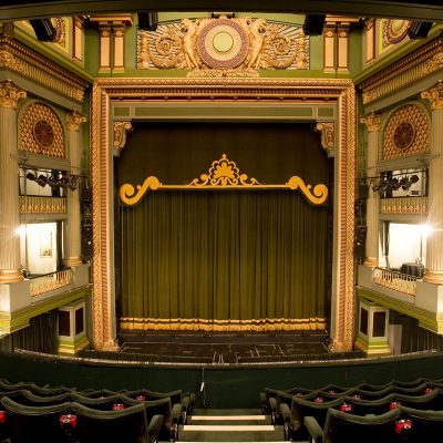 Empty theatre, with green curtains on the stage