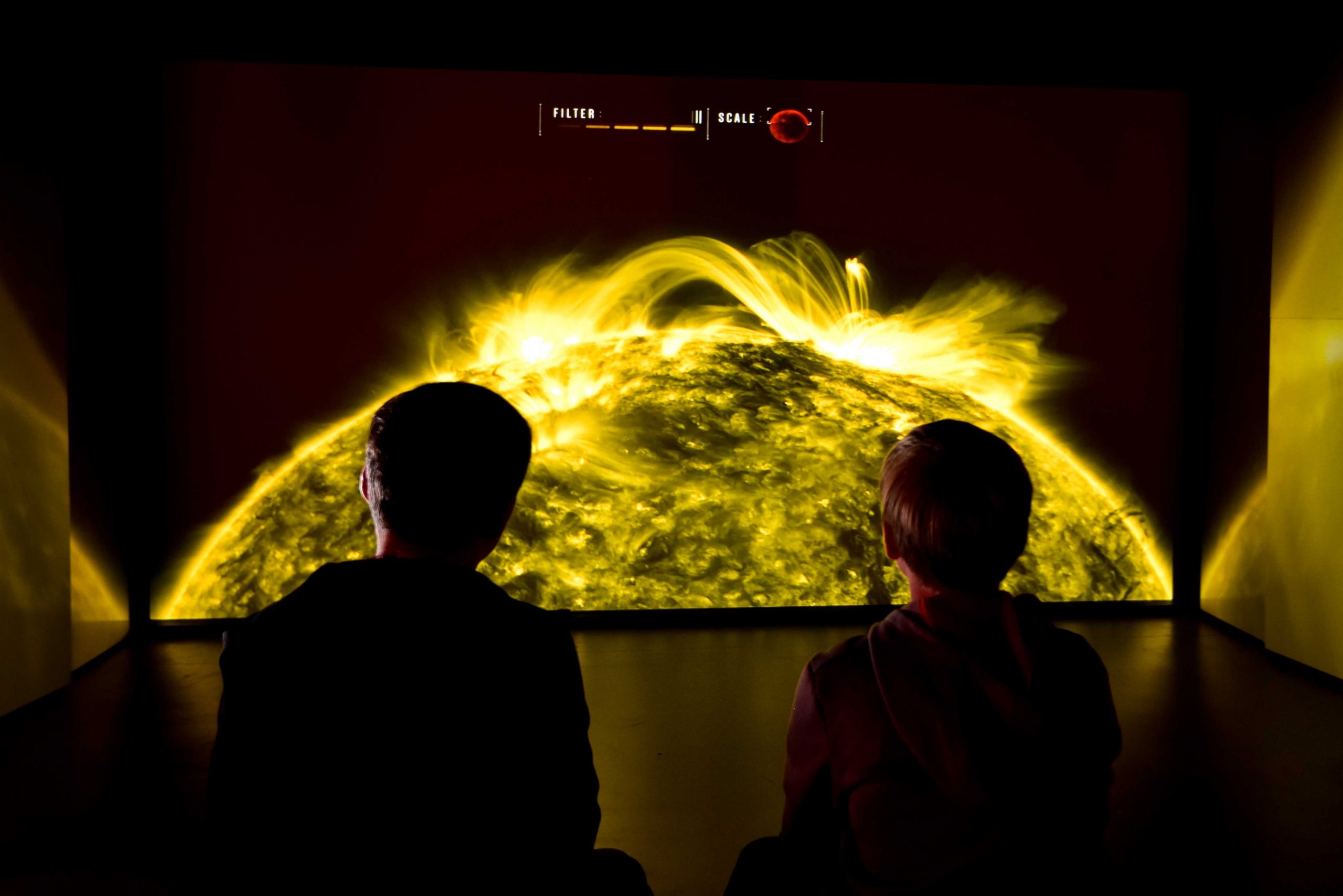 Two people in front of a picture of the sun