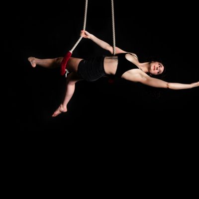 A woman hangs from ropes showing circus skills