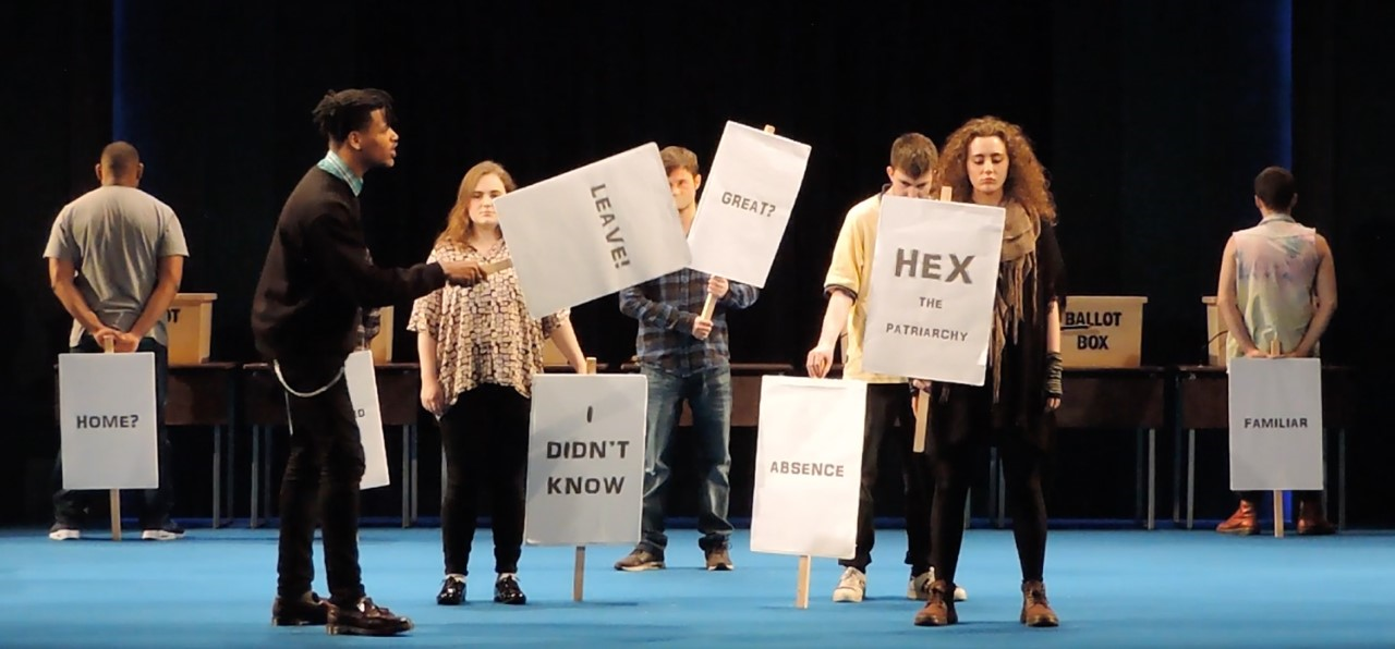 Young people on stage holding signs
