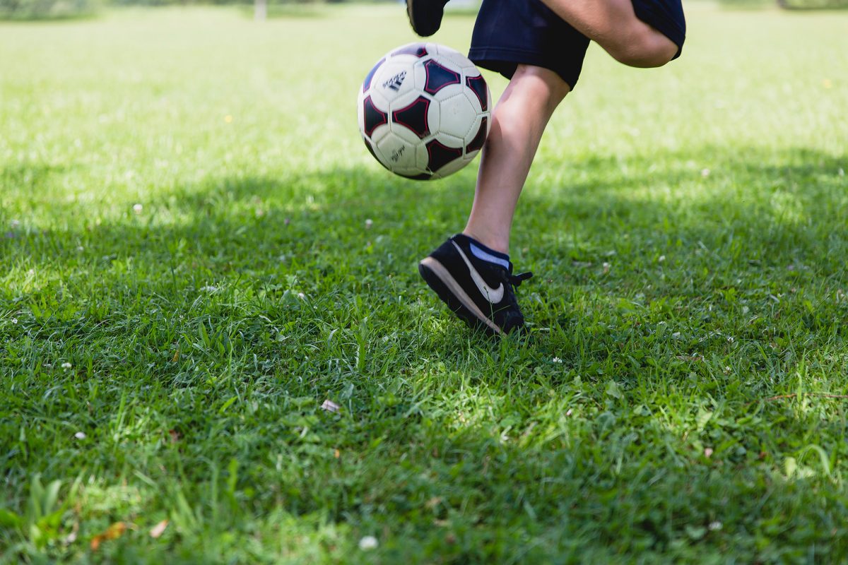 Closeup of child's legs as they play with a football