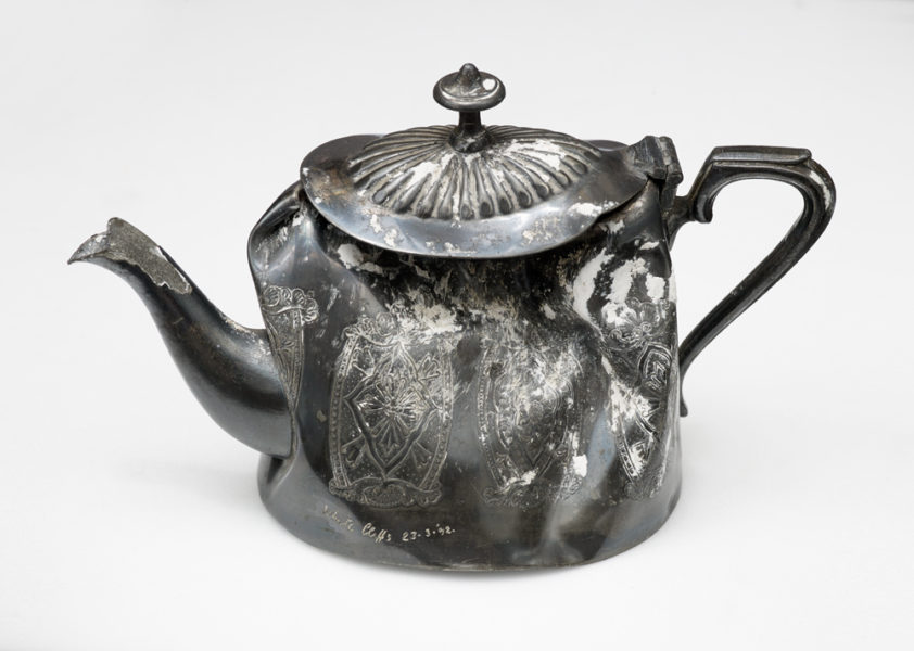 An well-used, dented and tarnished tea pot.