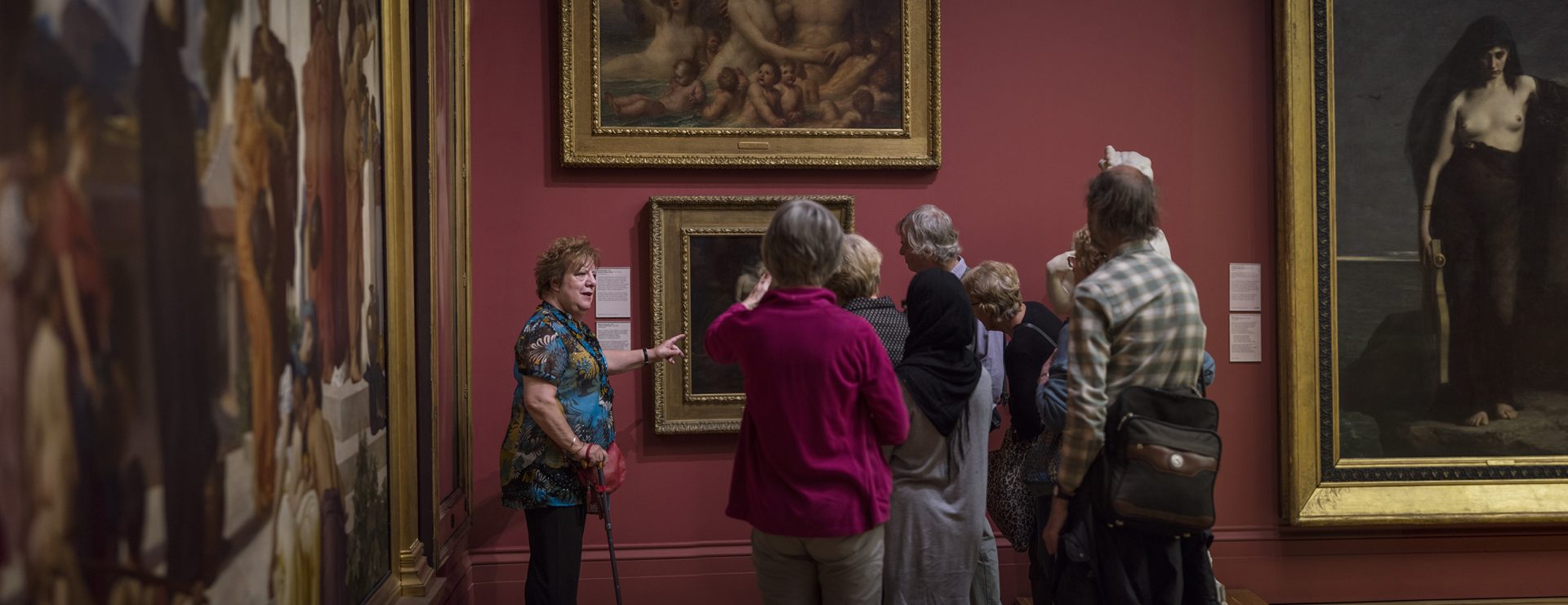 A small crowd of art lovers gather around a painting in a gallery.