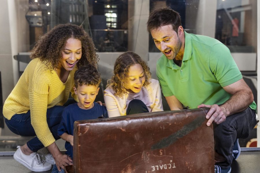 An excited family gather around a leather treasure chest.