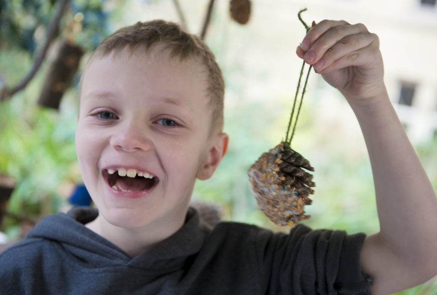 A young boy holding a rock smiles enthusiastically.