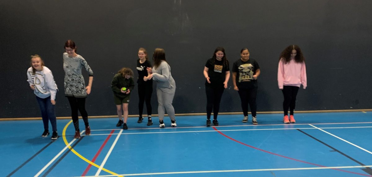 A group of young people ready to participate in a sports session in a sports hall.