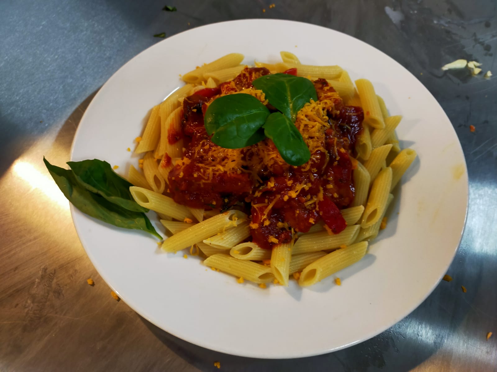 A bowl of warm pasta with bolognaise and basil leaves.