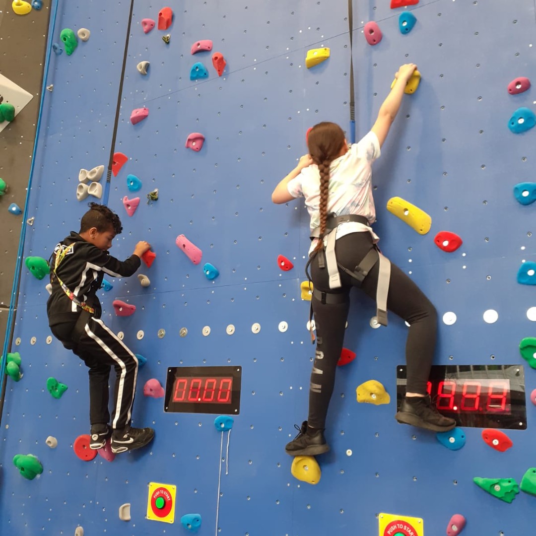 Two young people enjoy an indoor climbing session.