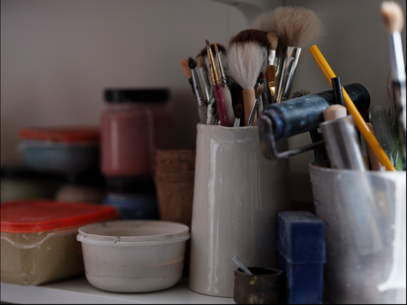 A variety of art materials, brushes and containers.