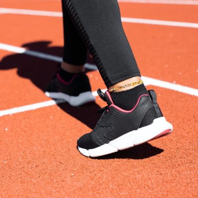 A person wearing black trainers in an athletics stadium