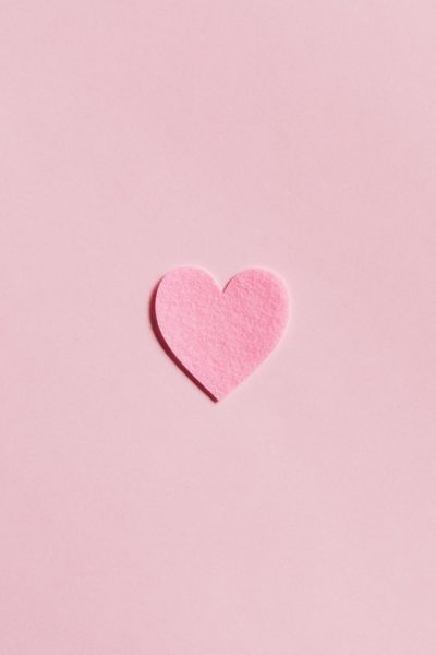 A pink felt heart placed on top of pink paper