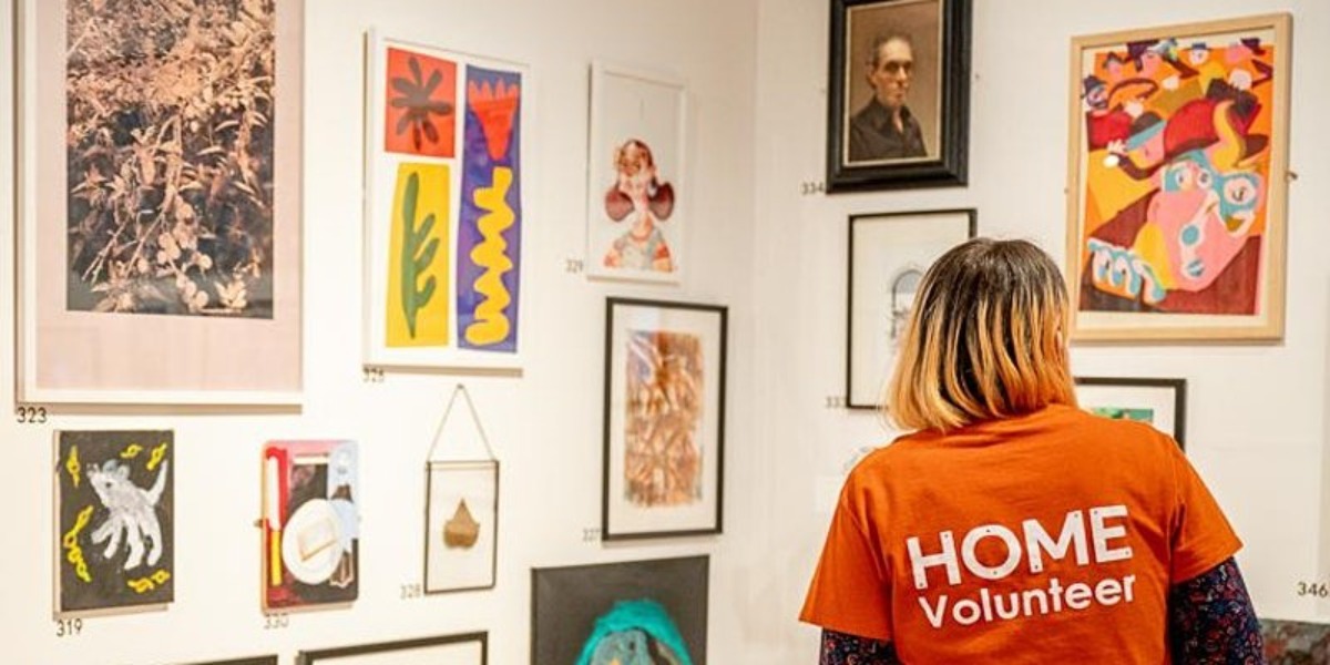 A HOME volunteer stands looking at artwork in a gallery