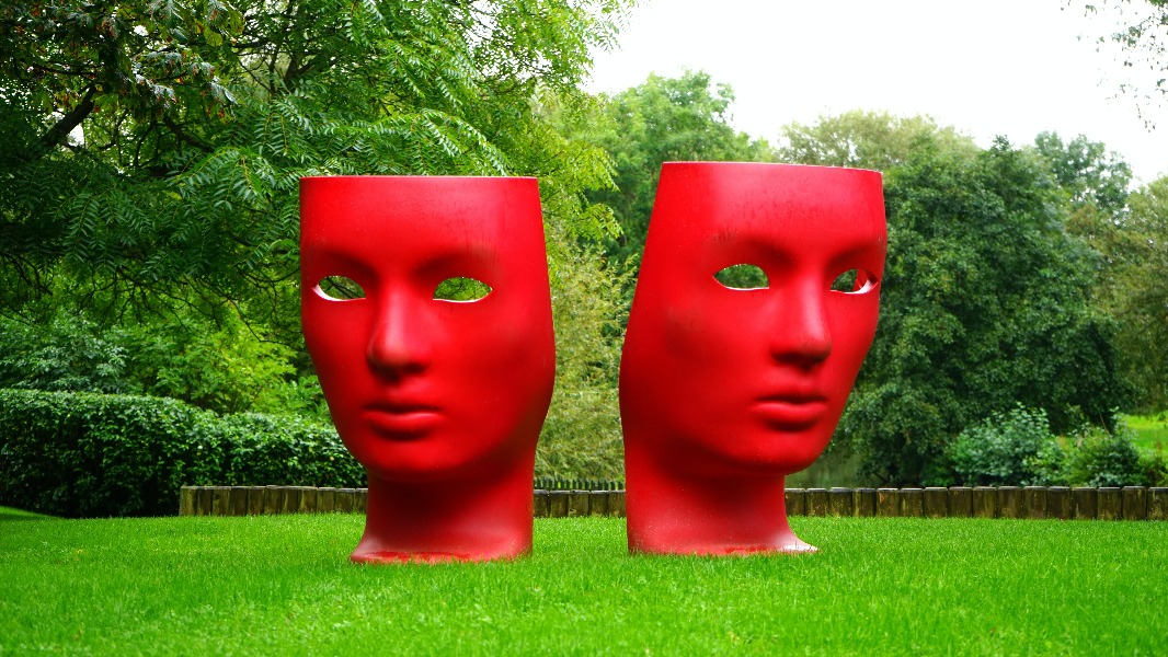An artwork of two large red faces in a grassy field