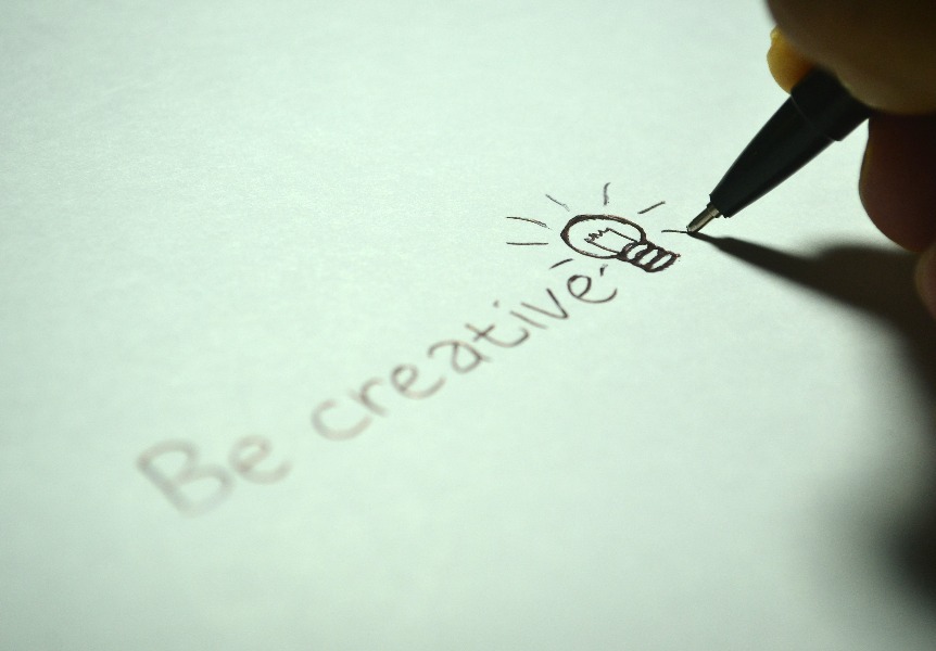A piece of paper with the words 'Be creative' written on it along with a drawing of a light bulb.
