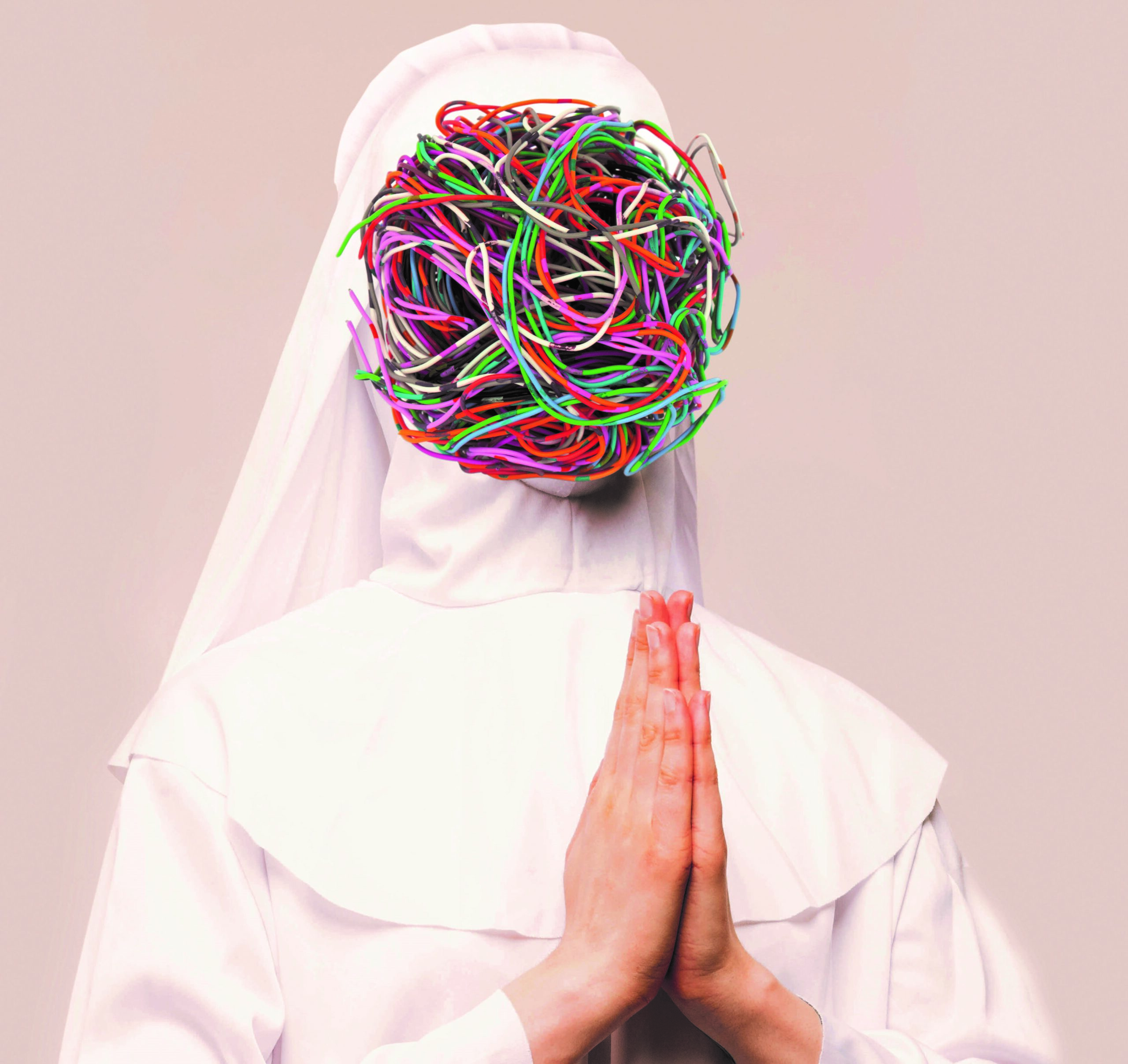 A nun stands, dressed in white, with a bunch of coloured electrical wires covering her face.