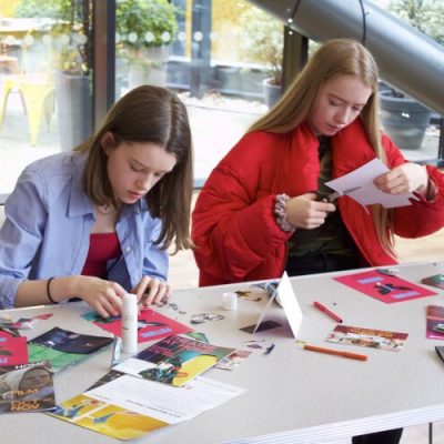 Two young people sat at a table doing craft activities.