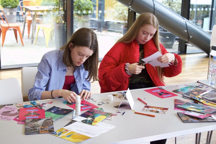 Two young people do craft activities at a table