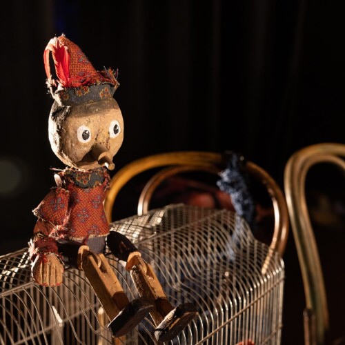 A wooden puppet sits on top of a chair