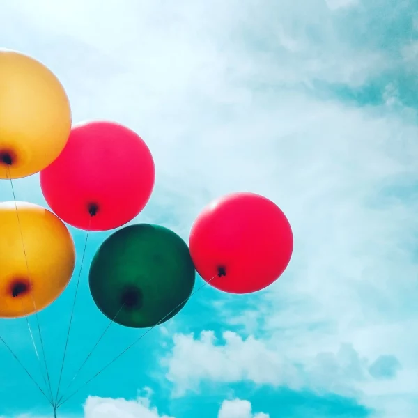 Red, green and yellow balloons against a blue sky