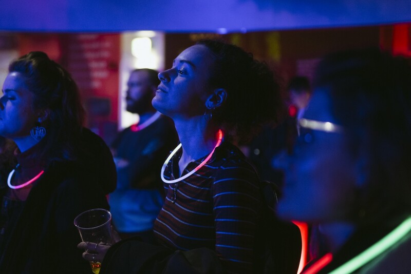 An audience watching a dark event wearing neon glow necklaces