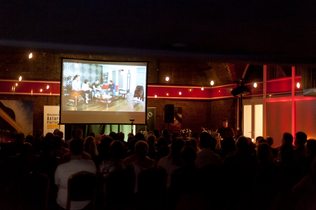 The interior of 53two with a big screen showing a film as an audience sits and watches.