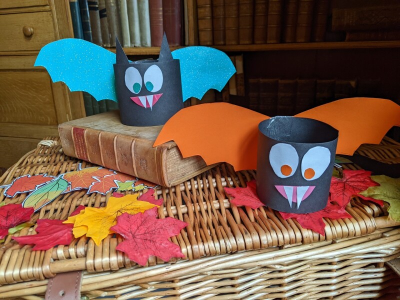 Two bats crafted from cardboard sit on top of a wicker basket.