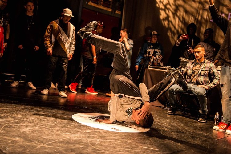 A breakdancer performs in front of a small group of people.