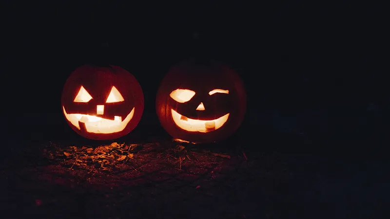 Two carved pumpkins are lit up at night.