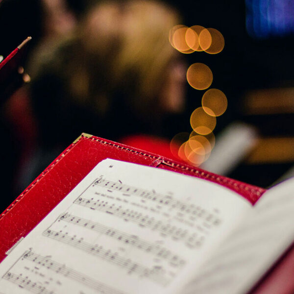 Photo of an open music score in a red folder with Christmas lights behind