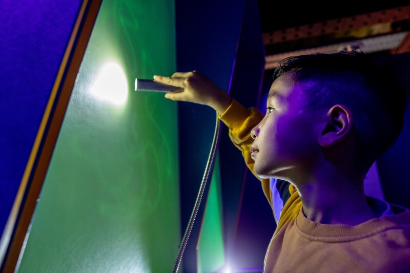 A young boy drawing with light on a wall at the Science and Industry Museum.