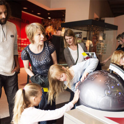 A family with two children explore a globe.