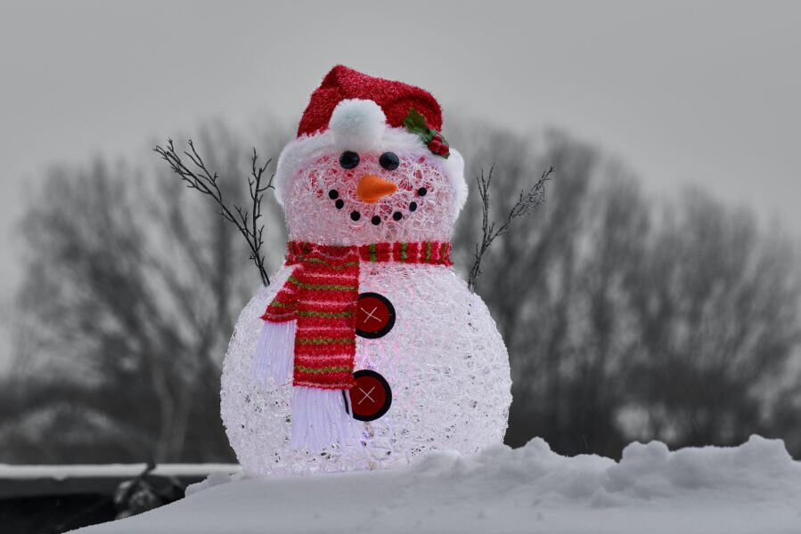 A snowman wearing a red Santa hat and scarf