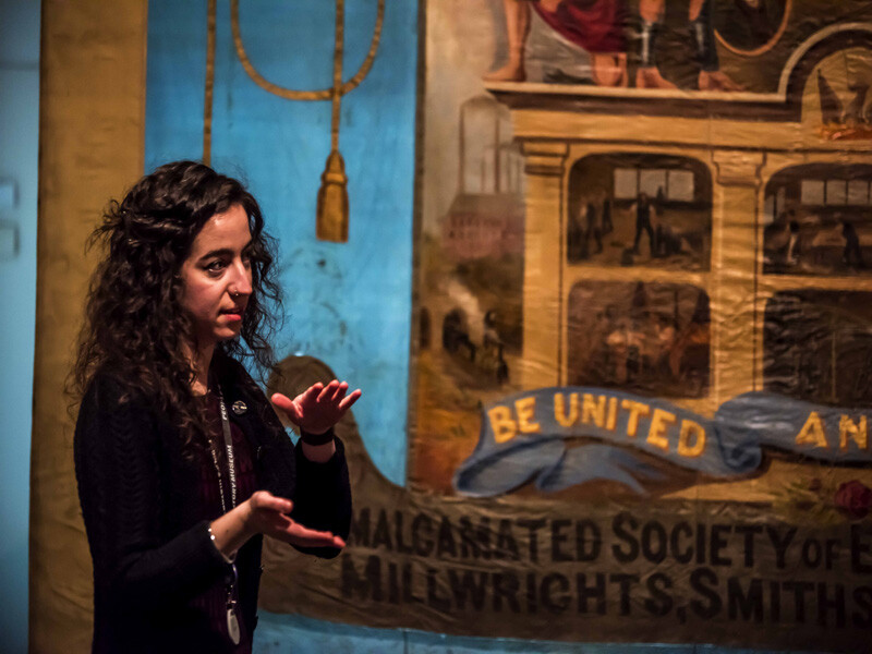 Conservator Kloe Rumsey in front of a banner including the words Be United