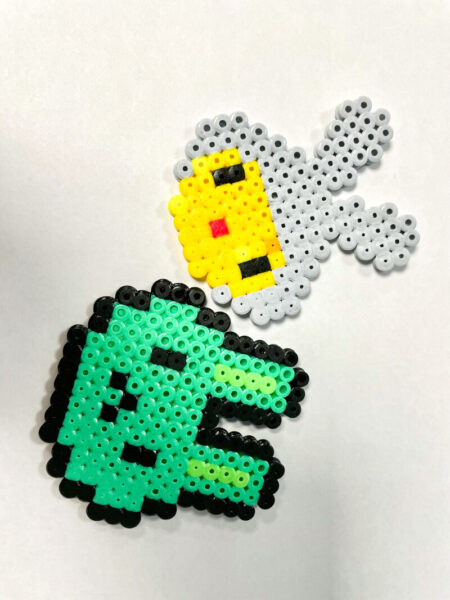 Two hand-crafted cartoon style hama bead bunny faces.