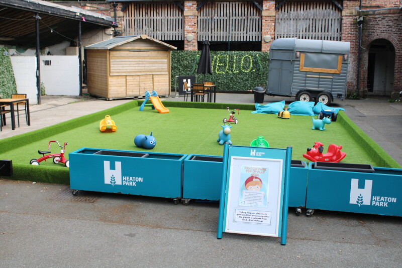 An astro-turfed and fenced safe play area with toys for young children.