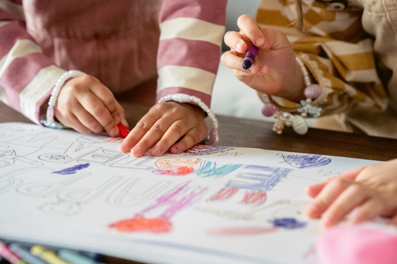Children using crayons to colour in an Easter colouring book.