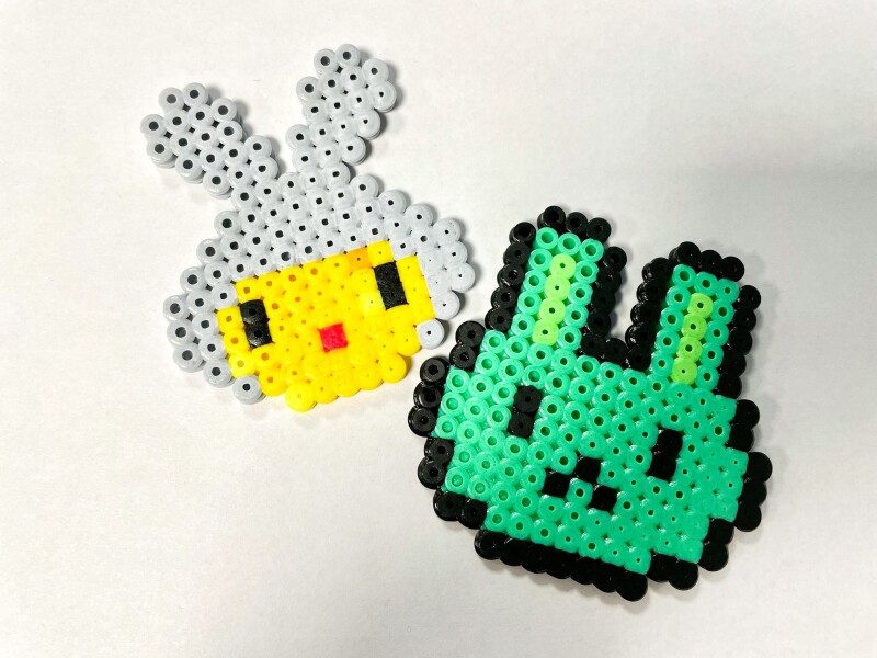 Two hand-crafted cartoon style bunny heads made from Hama Beads.