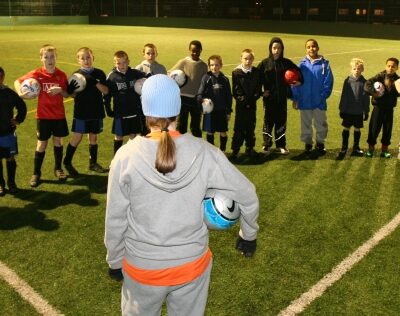 A team of young football players standing on the astro pitch at Benchill Community Centre with their coach.
