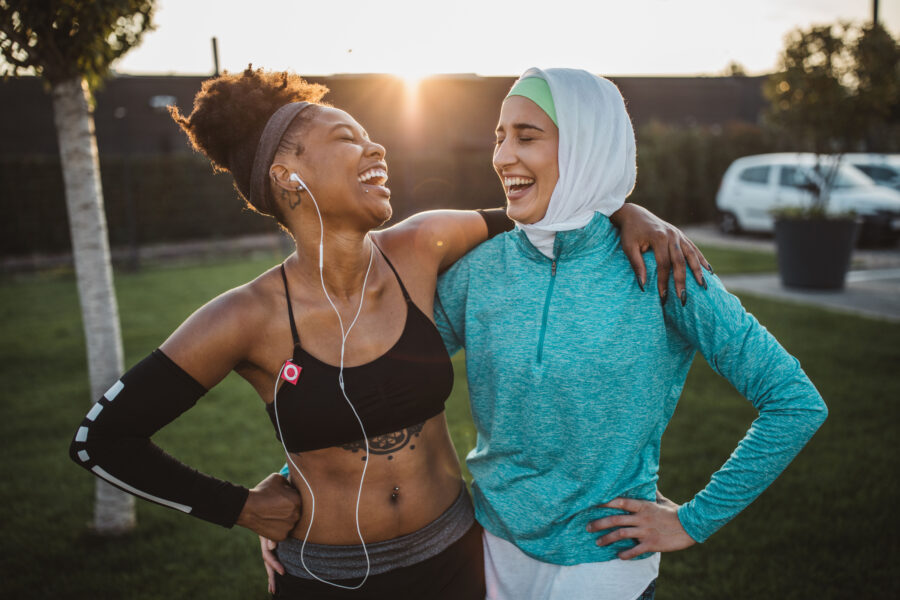 Two young women of different ethnicity dressed for exercise outdoors