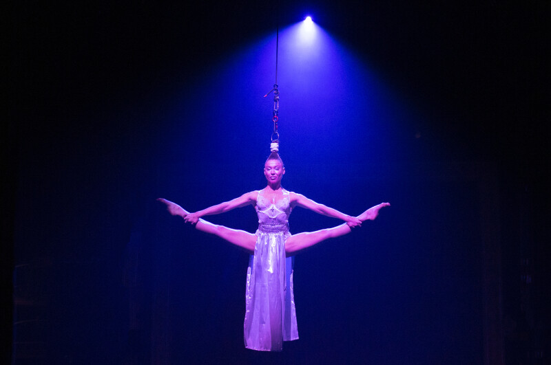A circus performer doing the splits suspended in the air.