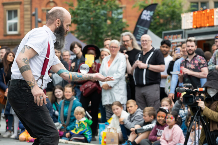 An entertainer stands in front of a crowd in Manchester city centre.