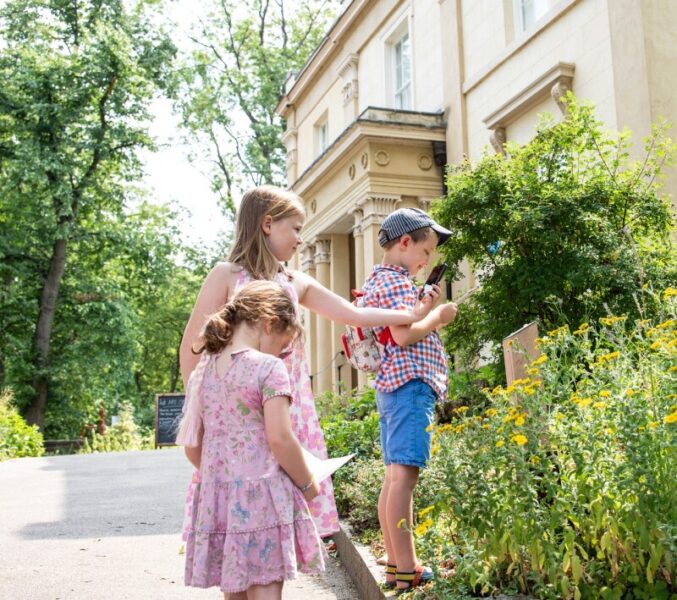 Two girls and a boy looking at the garden trail outside the house in the sunshine