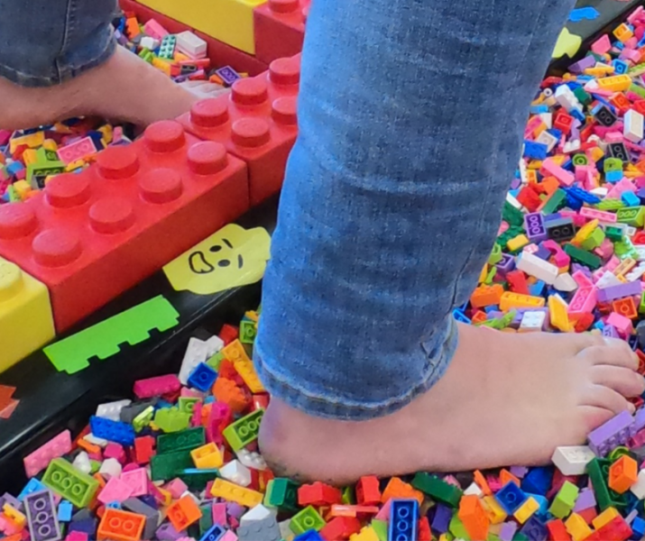 A person wearing jeans stands on top of a pile of Lego.