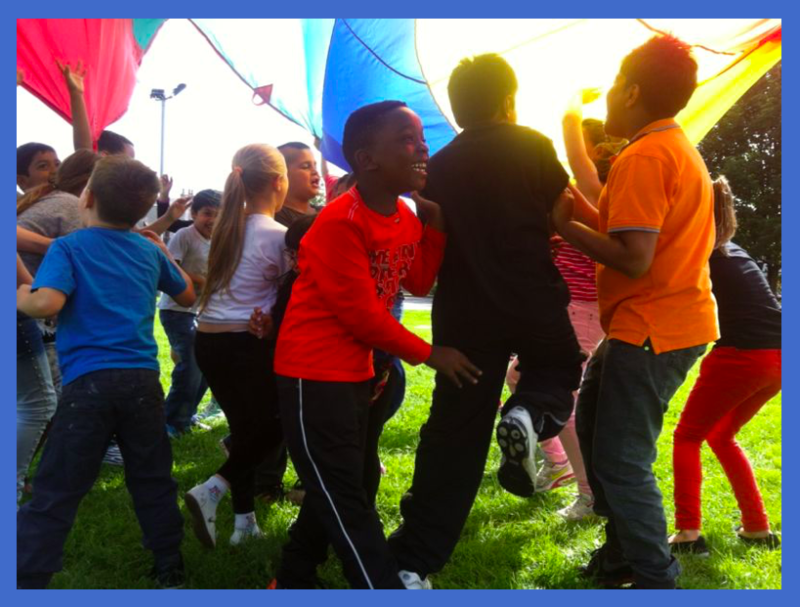 A group of children having fun, playing under a parachute.