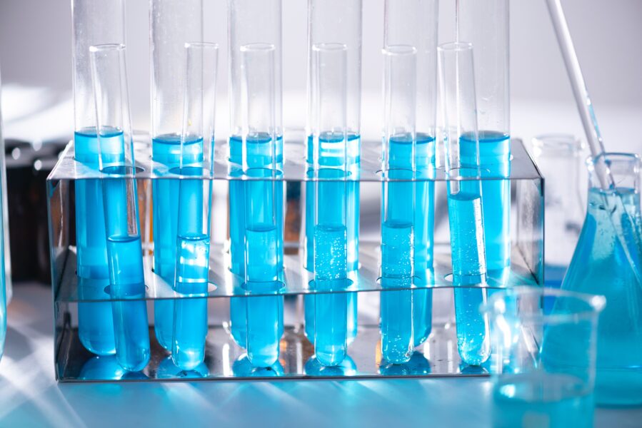 Seven test tubes containing a blue liquid in a stand.
