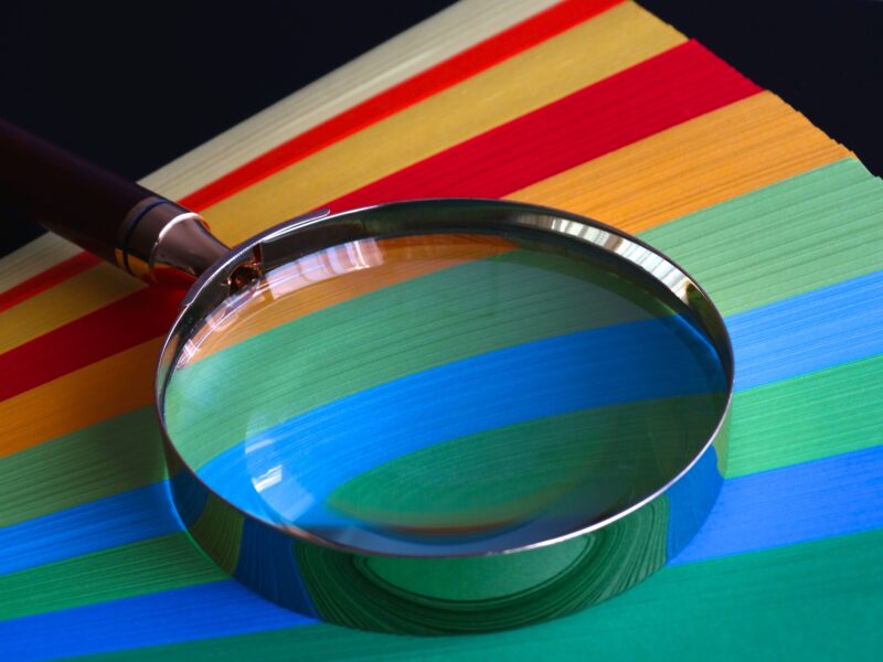 A magnifying glass set on top of different coloured paper.