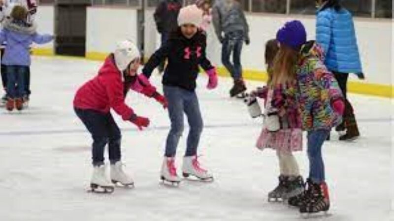 A group of young people ice skating.