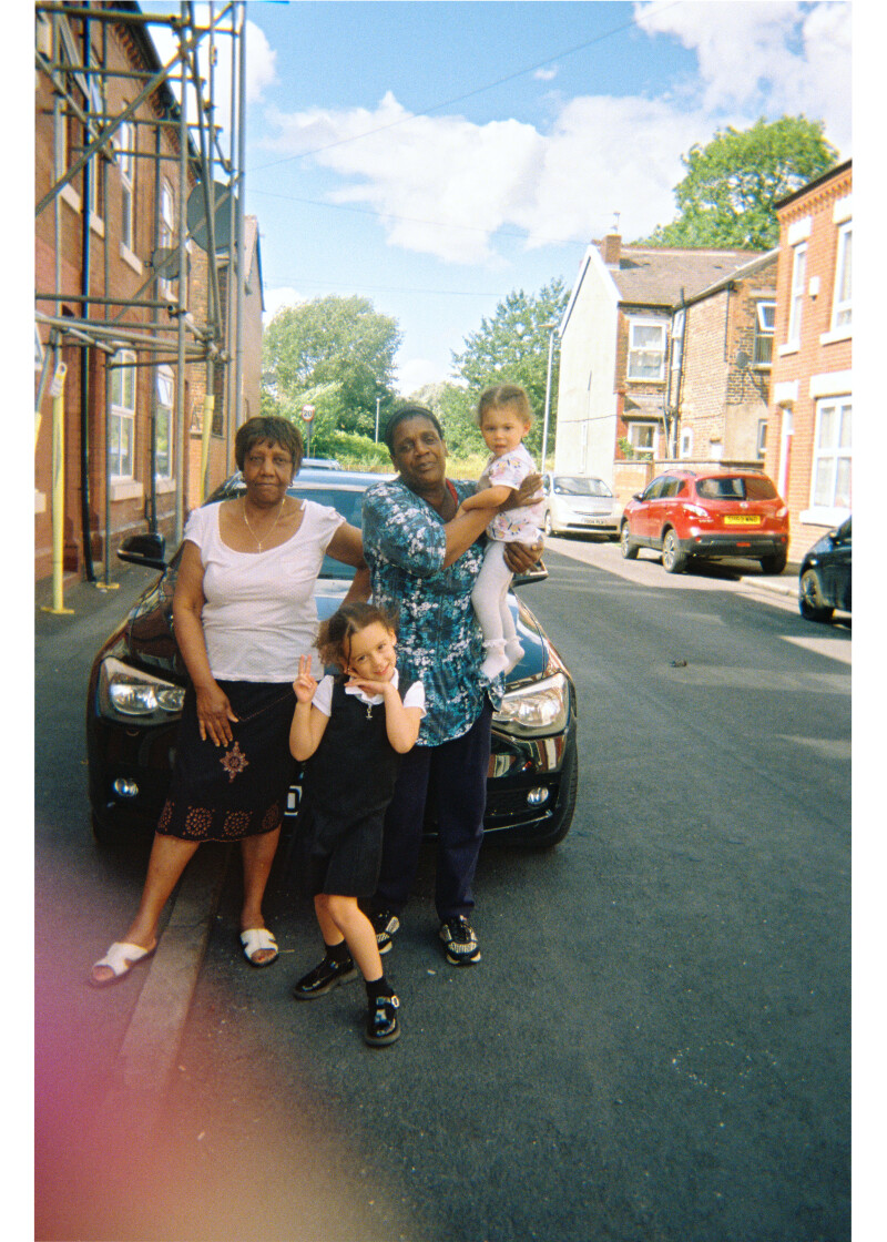 A family stand on the pavement on a residential street in Moss Side.